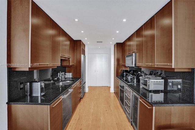 kitchen with light wood-style flooring, appliances with stainless steel finishes, decorative backsplash, and a sink