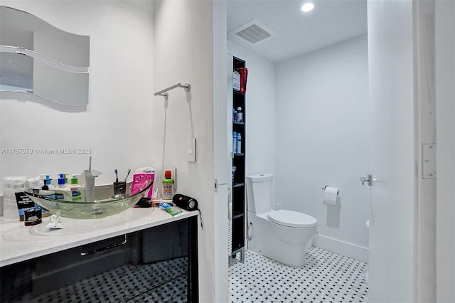 bathroom featuring baseboards, visible vents, vanity, and toilet