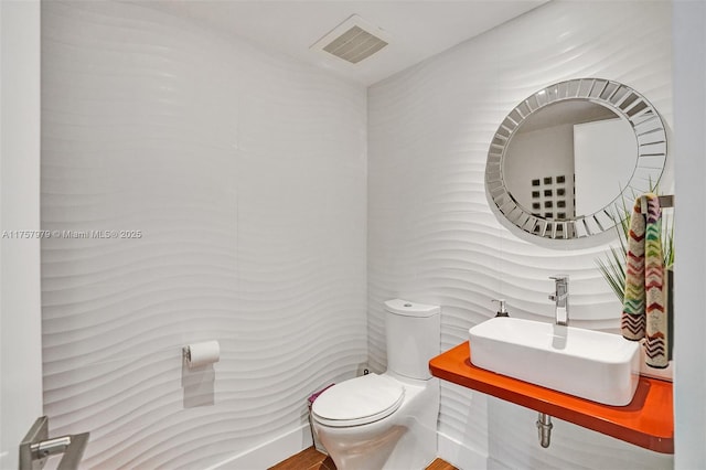 half bath featuring visible vents, a sink, and toilet