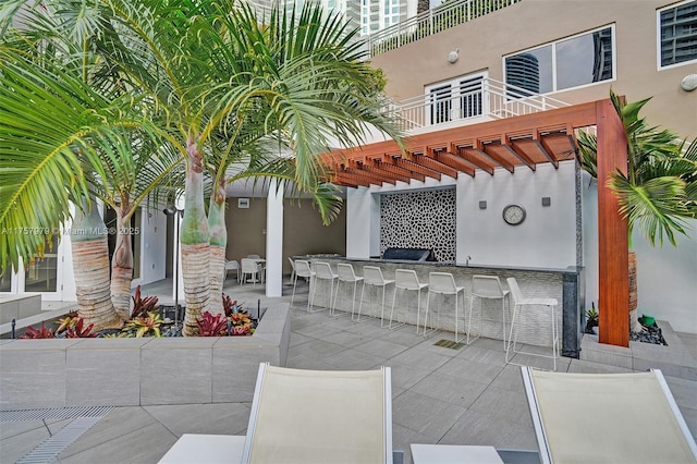 view of patio with a balcony, outdoor dry bar, and a pergola