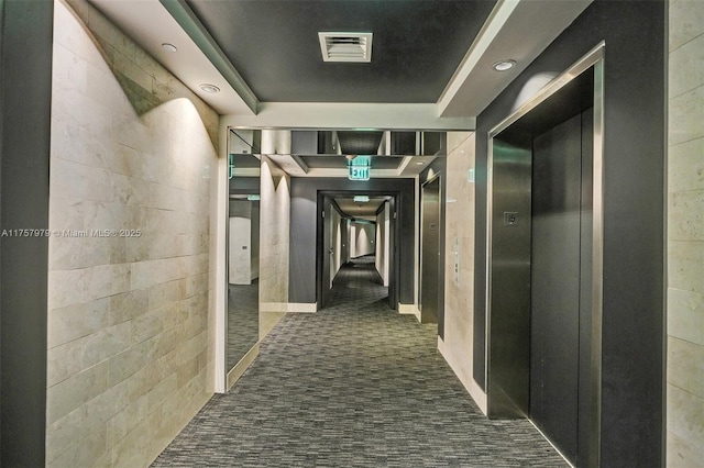 hallway with elevator, visible vents, a raised ceiling, and recessed lighting