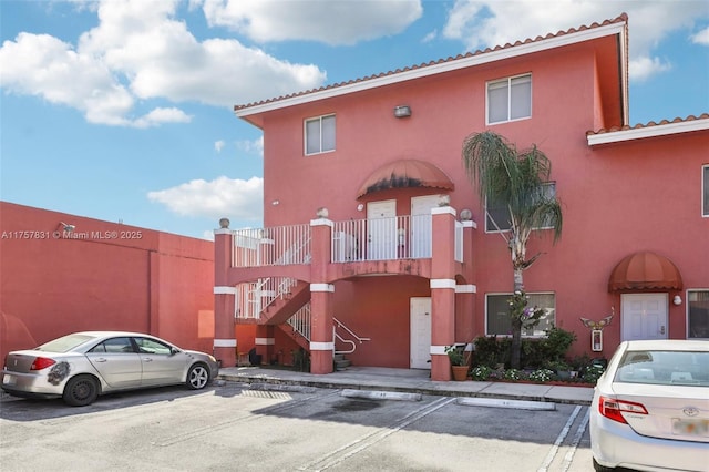 view of property featuring stairs and uncovered parking