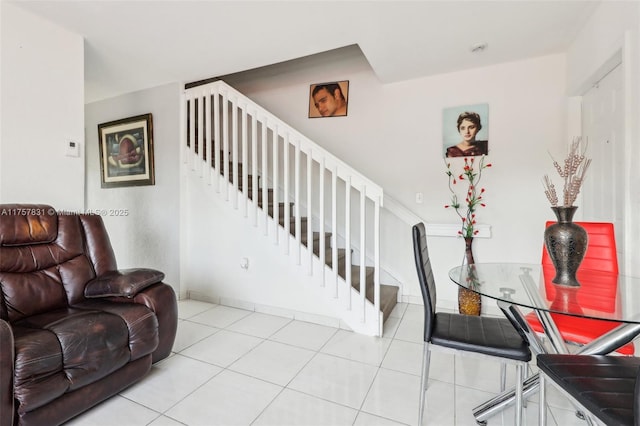 living room with light tile patterned floors, baseboards, and stairs