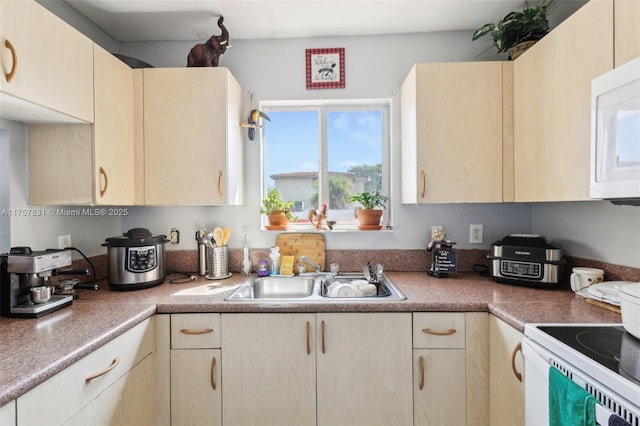 kitchen featuring light brown cabinets, light countertops, white appliances, and a sink