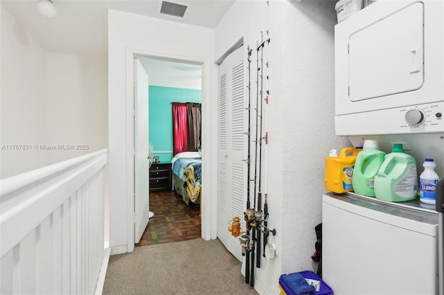 clothes washing area featuring stacked washer and dryer, laundry area, and visible vents