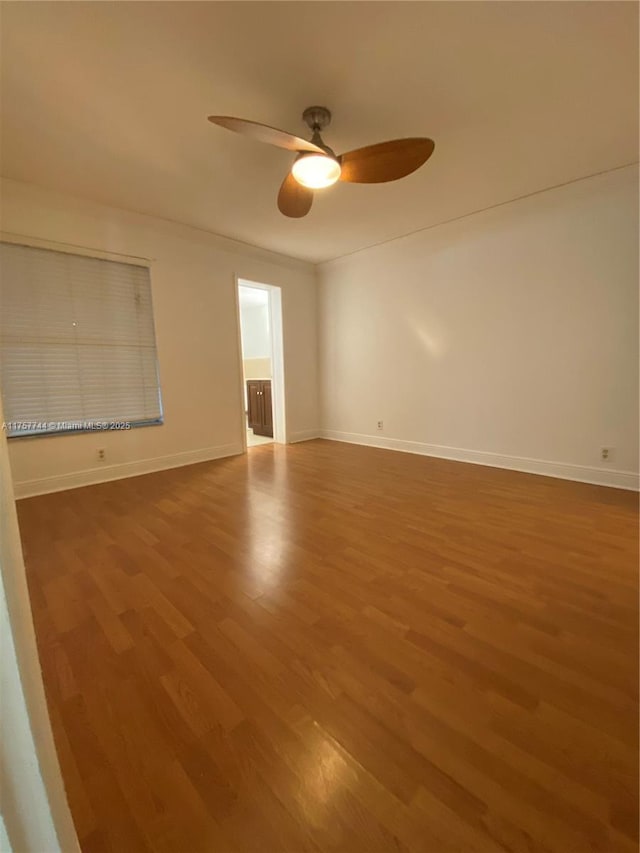 spare room featuring ceiling fan, baseboards, and wood finished floors