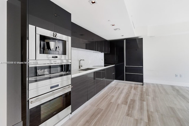 kitchen with light countertops, dark cabinetry, modern cabinets, and a sink