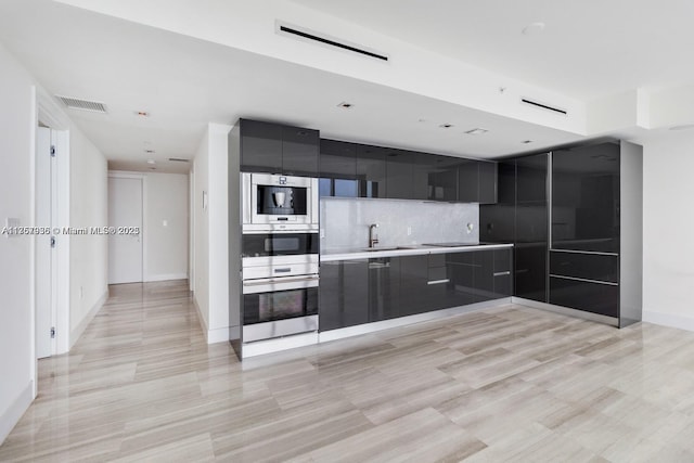 kitchen featuring light countertops, visible vents, backsplash, modern cabinets, and dark cabinetry