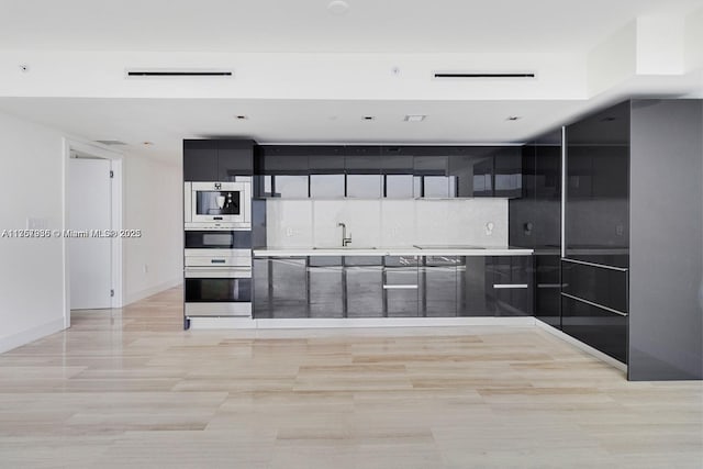 kitchen featuring dark cabinets, a sink, light countertops, tasteful backsplash, and modern cabinets