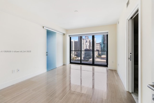 unfurnished room with a city view, visible vents, and baseboards