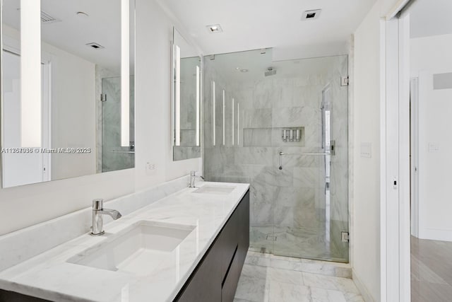 bathroom featuring marble finish floor, double vanity, a stall shower, and a sink