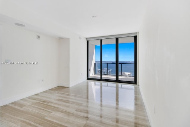 empty room featuring baseboards and a wall of windows