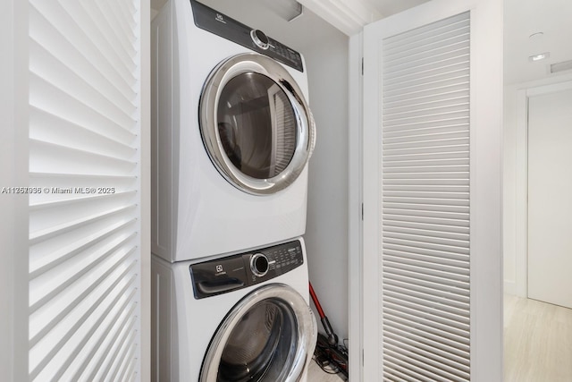 laundry room featuring laundry area, light wood finished floors, and stacked washer and clothes dryer