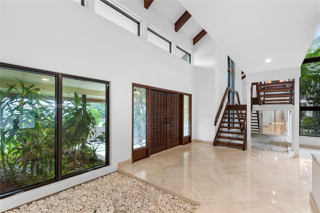 foyer entrance with a healthy amount of sunlight, a high ceiling, beam ceiling, and recessed lighting