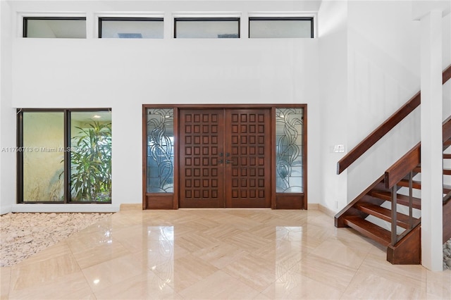 entryway with a towering ceiling, marble finish floor, and stairway