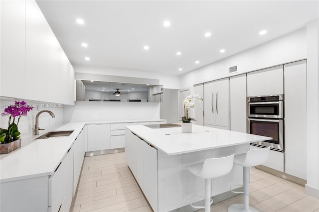 kitchen with black electric stovetop, modern cabinets, a sink, and visible vents