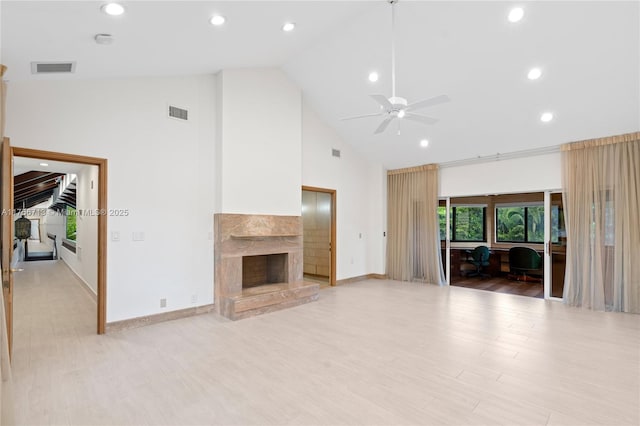 unfurnished living room featuring high vaulted ceiling, visible vents, baseboards, a high end fireplace, and light wood-style floors