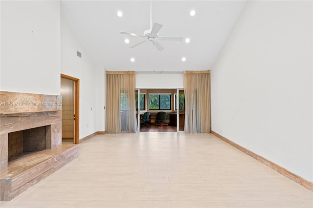 unfurnished living room with visible vents, a ceiling fan, light wood-type flooring, a fireplace, and high vaulted ceiling