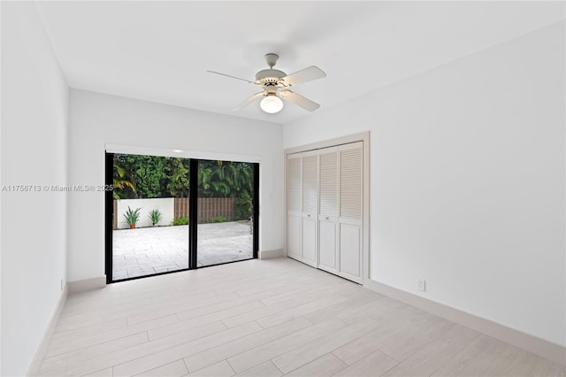 unfurnished bedroom featuring light wood-style floors, access to outside, baseboards, and a closet