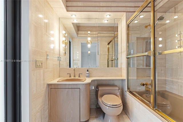 full bath featuring toilet, tiled shower / bath, tile walls, and vanity