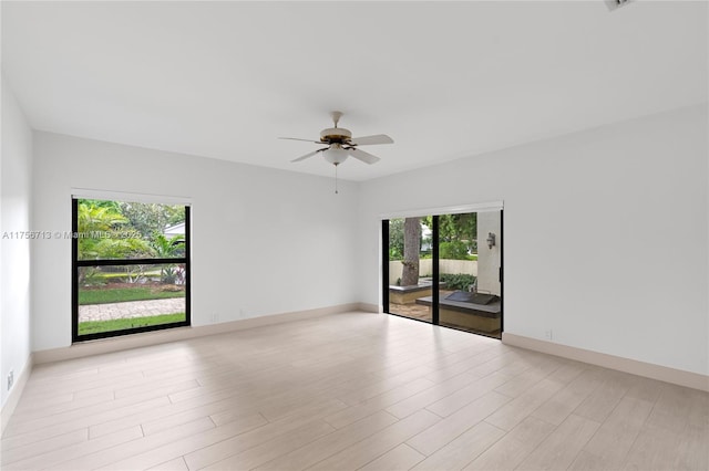 empty room featuring ceiling fan, light wood-style flooring, and baseboards