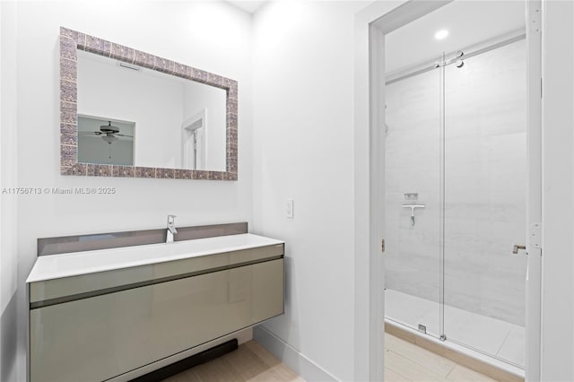 full bath with a ceiling fan, baseboards, a shower stall, and vanity