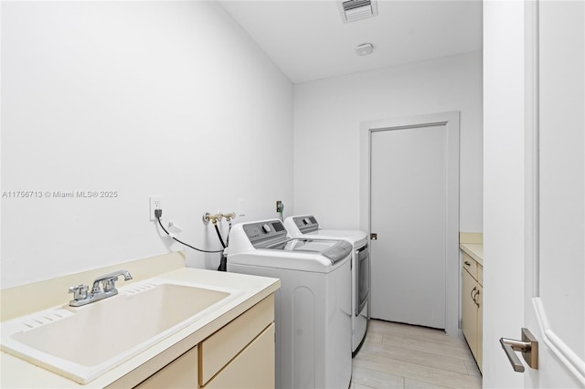 laundry area featuring a sink, cabinet space, visible vents, and washer and dryer