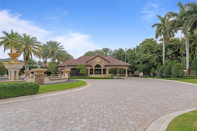 view of front facade featuring a tiled roof, decorative driveway, and stone siding