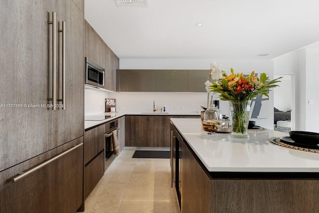 kitchen featuring light countertops, appliances with stainless steel finishes, modern cabinets, and a kitchen island