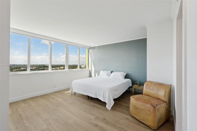 bedroom featuring light wood-style flooring, baseboards, and crown molding