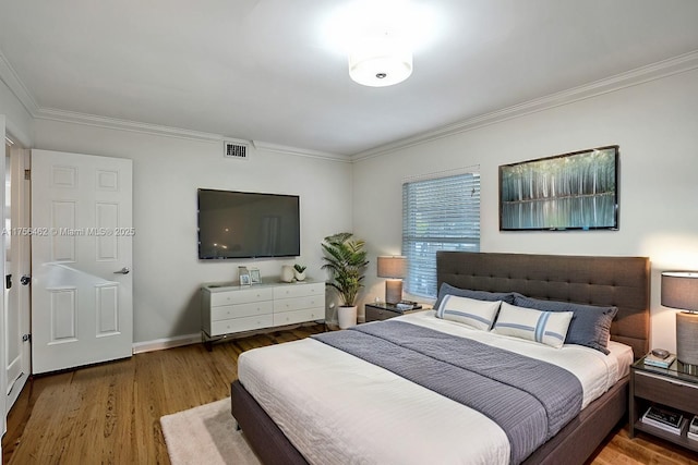 bedroom featuring visible vents, crown molding, baseboards, and wood finished floors