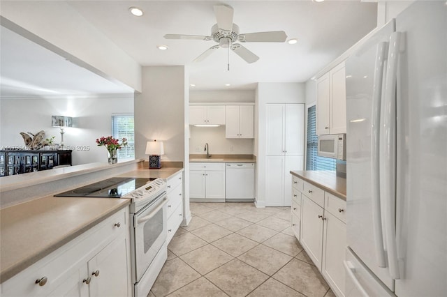 kitchen with white appliances, a sink, white cabinetry, and recessed lighting