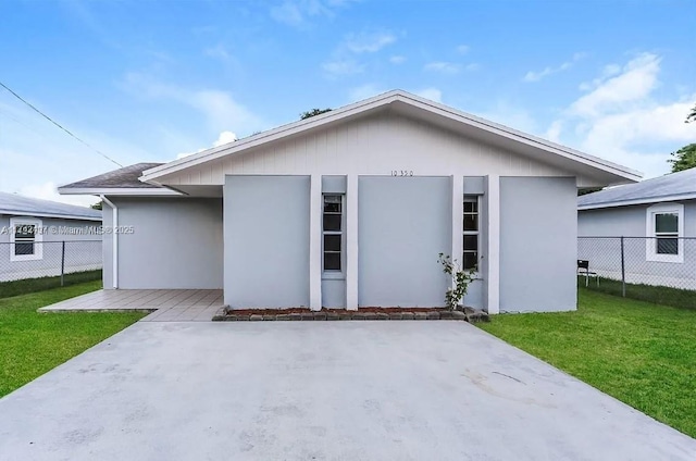 view of front of house featuring stucco siding, fence, a front lawn, and a patio