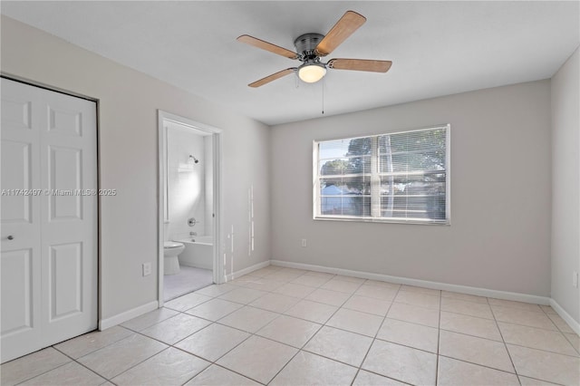 unfurnished bedroom featuring a closet, ceiling fan, baseboards, and light tile patterned floors