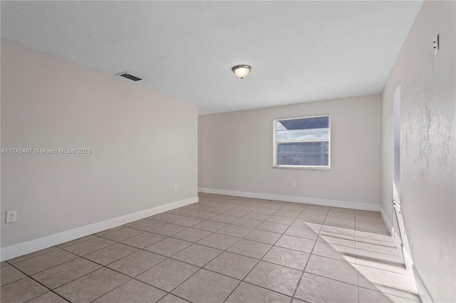 empty room featuring light tile patterned floors, visible vents, and baseboards