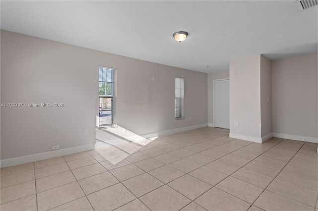 empty room featuring visible vents, baseboards, and light tile patterned floors