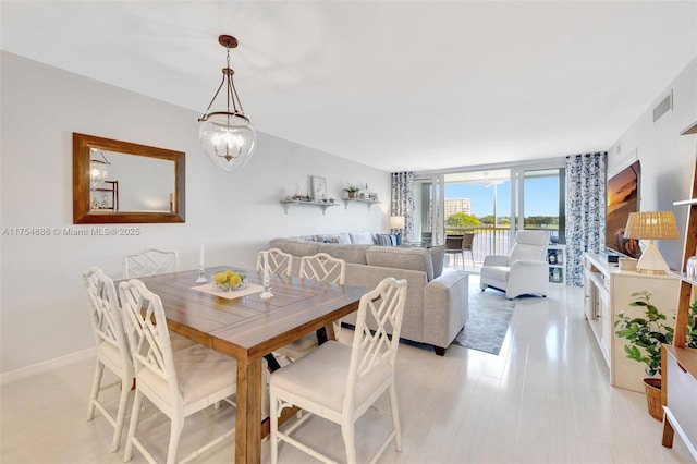 dining area with visible vents, baseboards, floor to ceiling windows, light wood finished floors, and an inviting chandelier