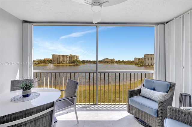 sunroom / solarium featuring a water view and a ceiling fan