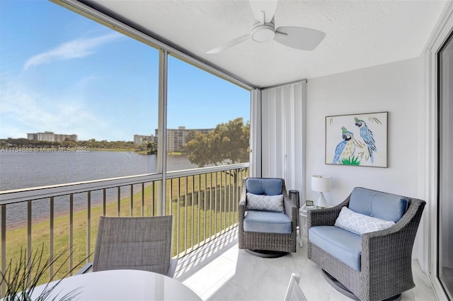 sunroom featuring ceiling fan and a water view