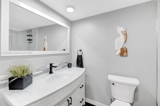 bathroom with baseboards, vanity, toilet, and walk in shower