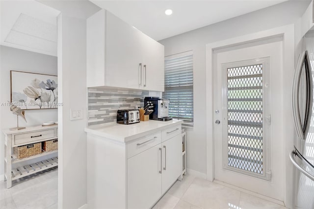 kitchen with white cabinets, tasteful backsplash, light countertops, and freestanding refrigerator