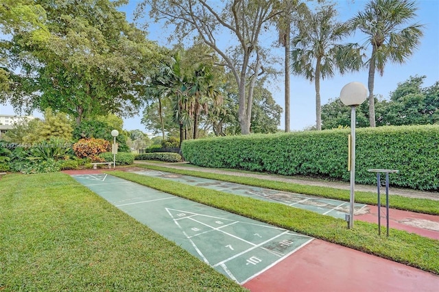 view of community with shuffleboard and a lawn