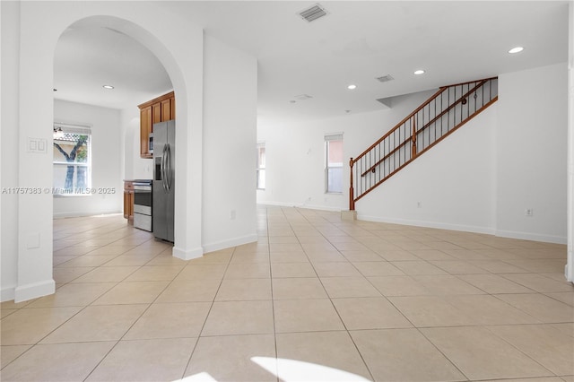 unfurnished room featuring arched walkways, light tile patterned floors, recessed lighting, visible vents, and stairway