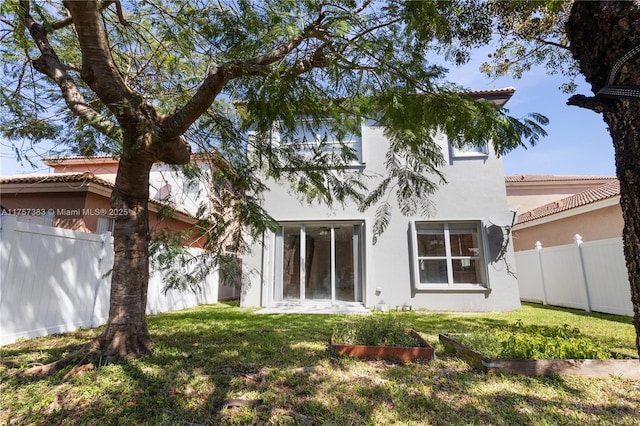 rear view of house with a yard, a fenced backyard, and stucco siding