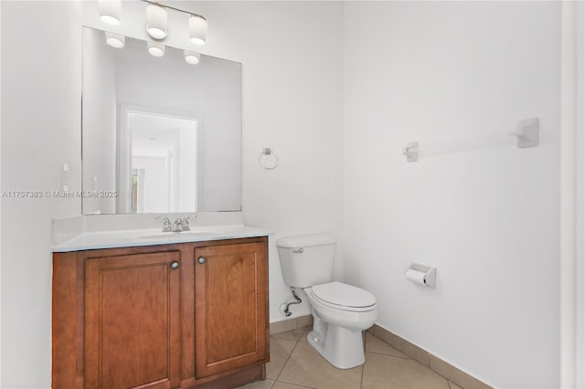 half bath featuring toilet, vanity, baseboards, and tile patterned floors