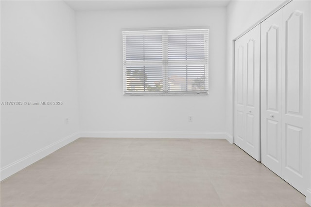 unfurnished bedroom with a closet and baseboards