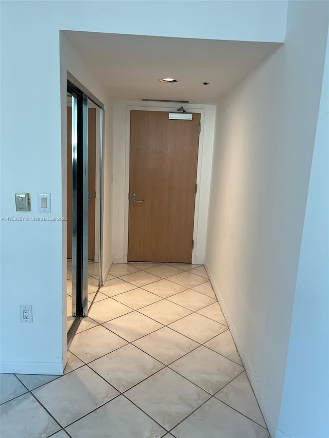 corridor with baseboards and light tile patterned flooring