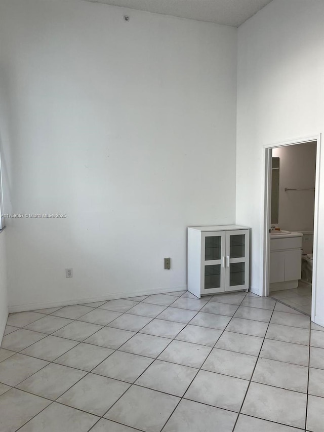 empty room featuring light tile patterned floors and a high ceiling