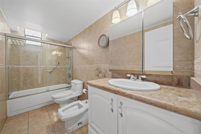 full bath featuring shower / bath combination with glass door, tile walls, toilet, vanity, and tile patterned flooring