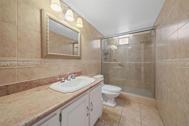 bathroom with tile patterned flooring, tile walls, a shower stall, and vanity